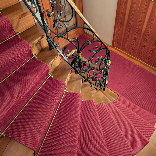 Einen Sisal Läufer an einer geschwungenen Treppe verlegt.
